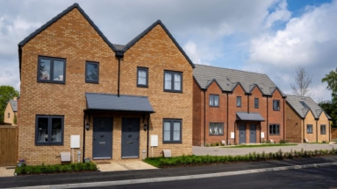 Exterior of a block red-brick of terraced houses with a street running in front of them in the foreground